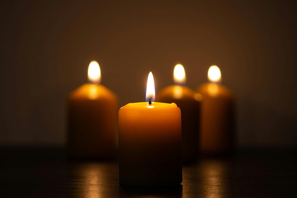 A serene image of four candles glowing warmly in a dimly lit room, evoking tranquility.