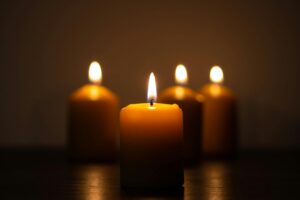 A serene image of four candles glowing warmly in a dimly lit room, evoking tranquility.